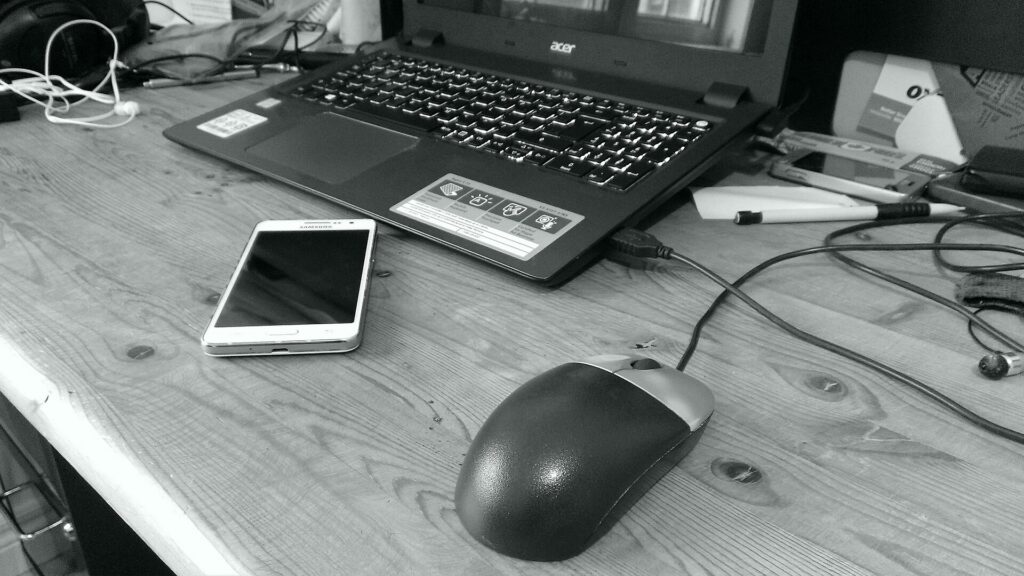 Computer mouse laptop and phone on a desk