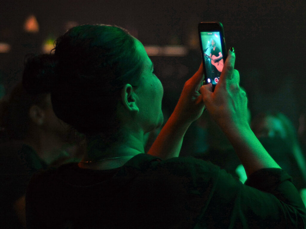 Woman taking a picture with her phone during a show