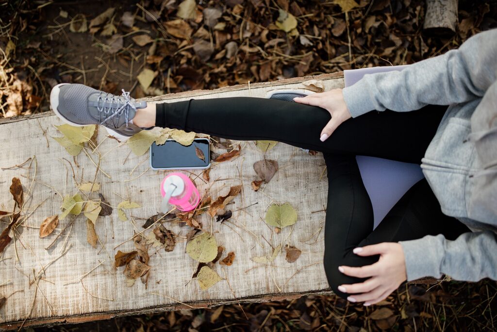 Casual outdoor relaxation with phone and drink amidst autumn leaves in a peaceful setting