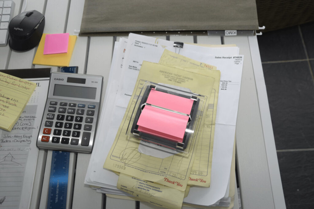 EFTA00003028-Beach-House - Cluttered desk with papers sticky notes a calculator and a mouse suggesting busy work
